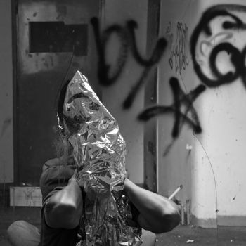 Obscured man and broken mirror in abandoned interior. Black and white.