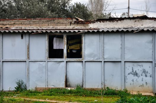 Rusty warehouse shack with drying laundry by the window.
