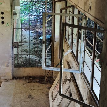 Rusty windows and door frame in abandoned house interior.