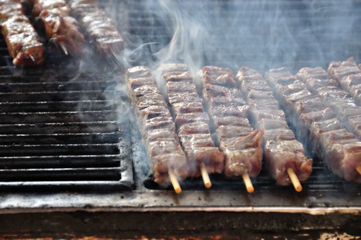 Souvlaki meat skewers on hot grill. Greek food background.