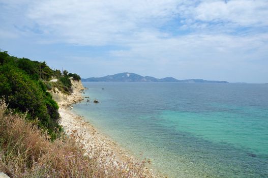 Eroded stone beach blue sea and sky horizon. Zakynthos, Greece.