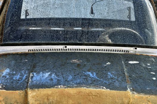 Vintage car scraped hood and rain covered windscreen.