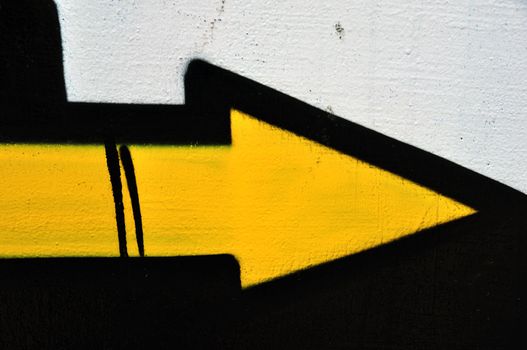 Yellow arrow graffiti sprayed on wall. Abstract background texture.