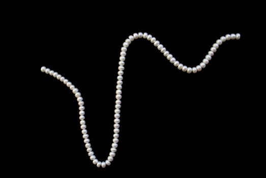 White pearls on the black silk as background 