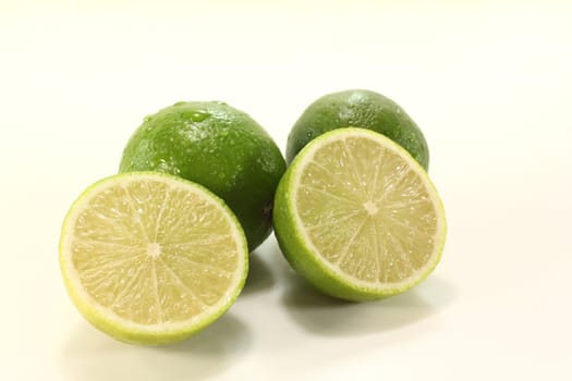 green sliced and whole limes on a light background