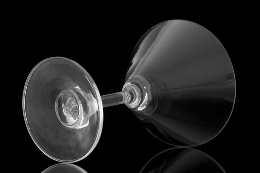 Empty cocktail glass lay on black background and reflect