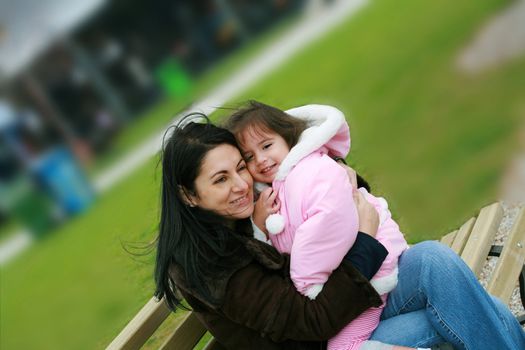 Diverse mom and daughter sitting in the bench