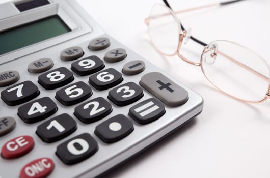 Business background with calculator and glasses isolated in white