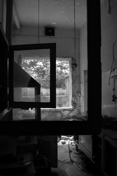 Broken window frames and reel tape on abandoned factory floor. Black and white.