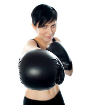 A female wearing black boxing gloves throwing a punch towards camera