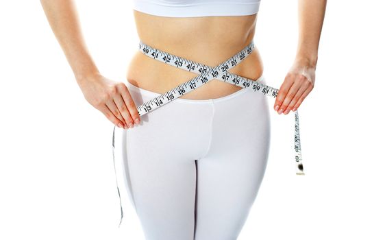 Slim female body shown while measuring waist width with tape metre