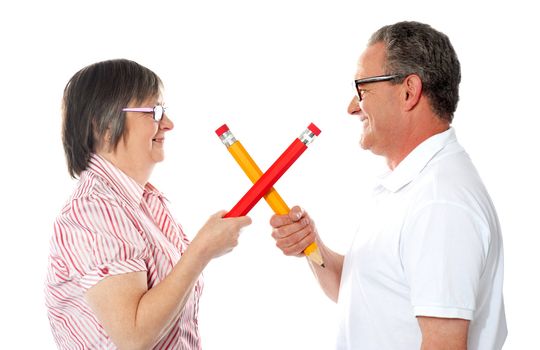 Smiling couple with two big pencil showing symbol of cross