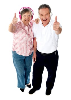 Thumbs-up couple tuned into music, isolated over white