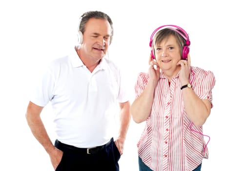 Happy aged couple enjoying music together in studio. Isolated over white