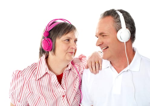 Romantic senior couple enjoying music together. Wife resting her hand on shoulders of her man