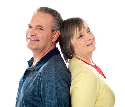 Aged couple smiling and posing back to back in front of camera