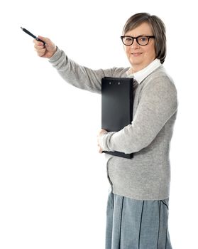 Female executive pointing away with pen in hand. Carrying business documents