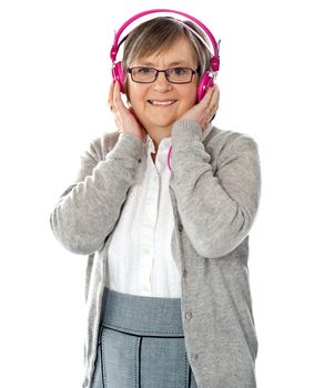 Attractive old lady wearing headphones listening music