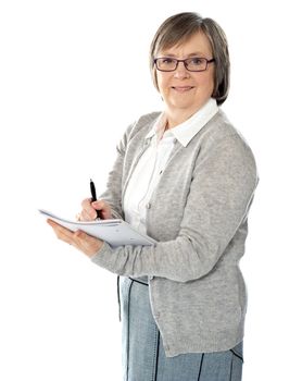 Aged woman writing on spiral notebook. Isolated against white background