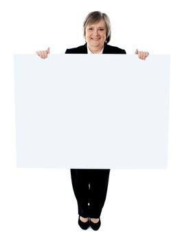 Smiling businesswoman holding a blank poster against white background