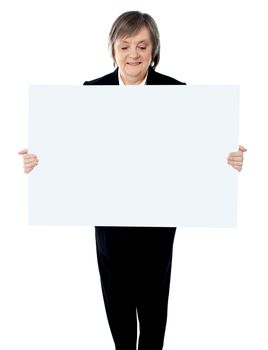 Portrait of happy aged woman holding a blank billboard over white background