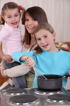 Mother and two young daughters cooking