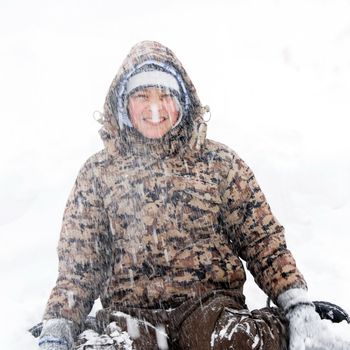 portrait of caucasian teenage boy in hood at winter outdoors, at snowfall