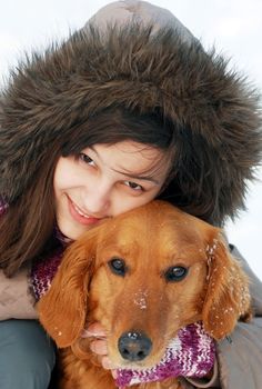 smiling teenager caucasian girl in hood hugging her dog outdoors