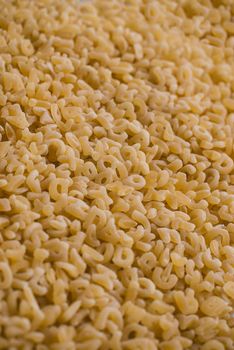 Close-up background of alphabet noodle showing letters.