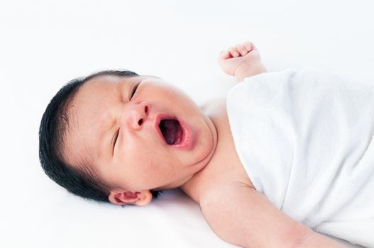 Portrait of a newborn infant baby yawning over white background.