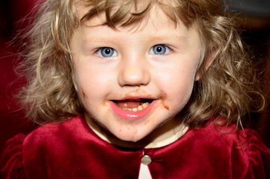 The photo shows a portrait of a little girl who misfed paper to soil themselves with chocolate face.
