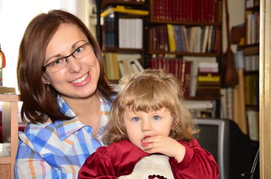 The photo shows a young woman holding a baby girl in her lap.