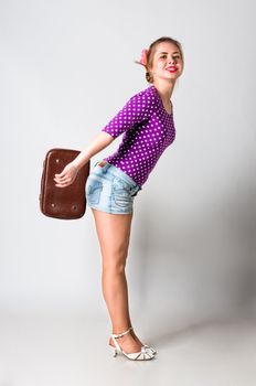 Pin up girl standing with bag and smiling, studio shot