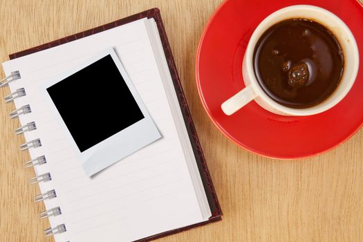 cup coffee and photo frame and notebook on wood background