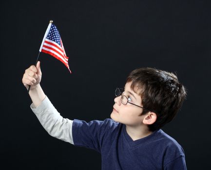 Boy with American flag over black background