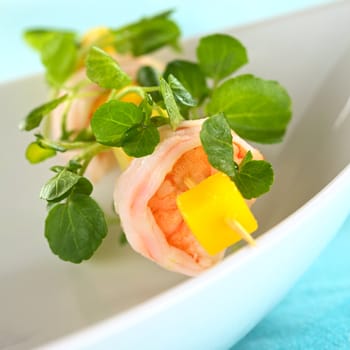 Fresh cooked shrimp and mango on skewer with watercress leaves on bowl (Selective Focus, Focus on the upper rim of the shrimp)