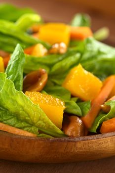 Fresh spinach, mango and carrot salad with peanuts on wooden plate (Selective Focus, Focus on the front of the salad)