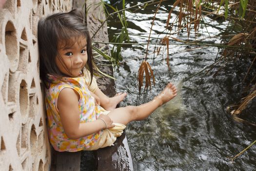 The playful girl sprays feet pond water 