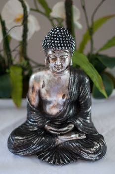 Silver Buddha figure with calla lilies background - face with shallow dof