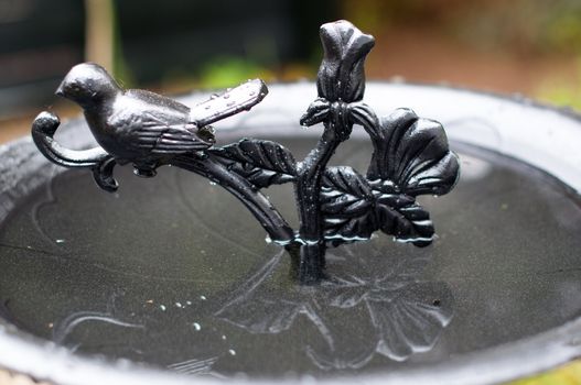 A richly decorated metal birdbath in a garden