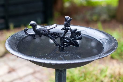 A richly decorated metal birdbath in a garden