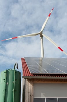 barn covered with solar panels and wind turbine in the background
