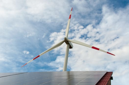 barn covered with solar panels and wind turbine in the background