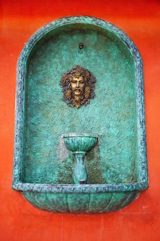 A head water fountain on red wall