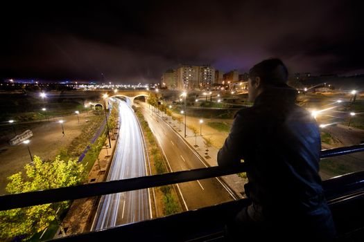 Night cityscape with road and young man