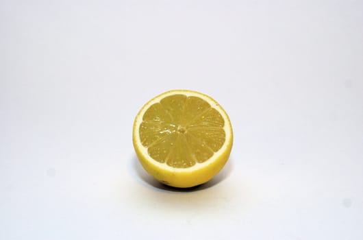 Half a cut lemon with segments visible against a white background with copy space