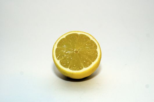 Half a cut lemon (centered) with segments visible against a white background with copy space