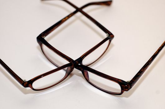 Two pairs of tortoiseshell spectacles/ glasses on a white background with copy space