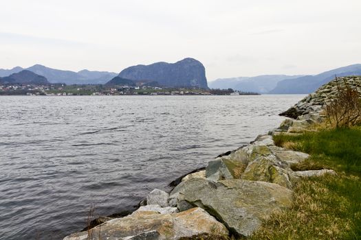 stony coast in norway with mountains in background