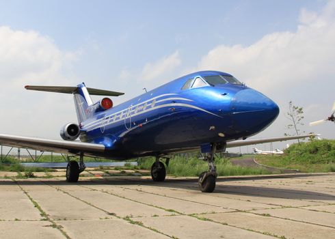 Shiny  blue jet aircraft on airfield against sky background